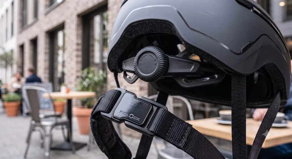 Gros plan sur la molette de réglage ErgoFit et la boucle magnétique Fidlock d'un casque trottinette